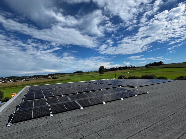 Großes Dach mit PV-Anlage, im Hintergrund blauer Himmel.