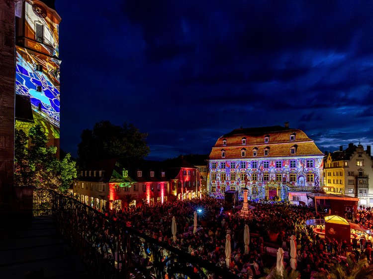 Fest am Museum Lindauer Stadtmueum bei Nacht mit farbenfroher Lichtprojektion auf historischen Gebäuden und großer Menschenmenge.