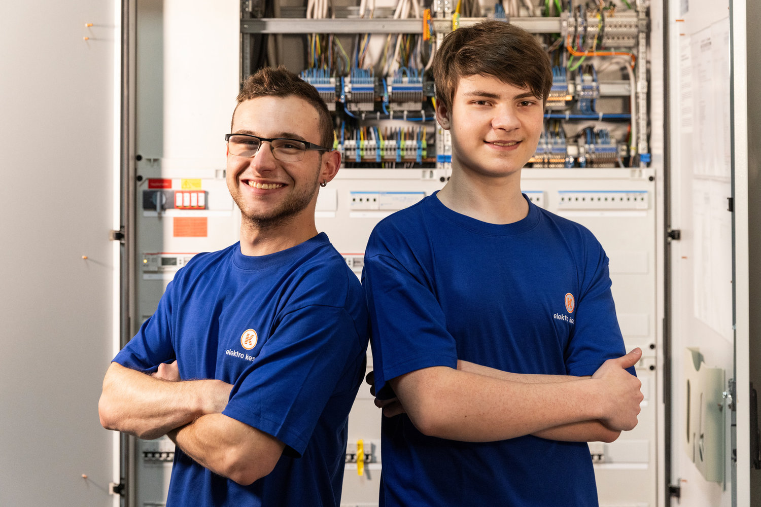 Zwei Mitarbeiter von Elektro Kessler stehen vor einem Sicherungskasten
