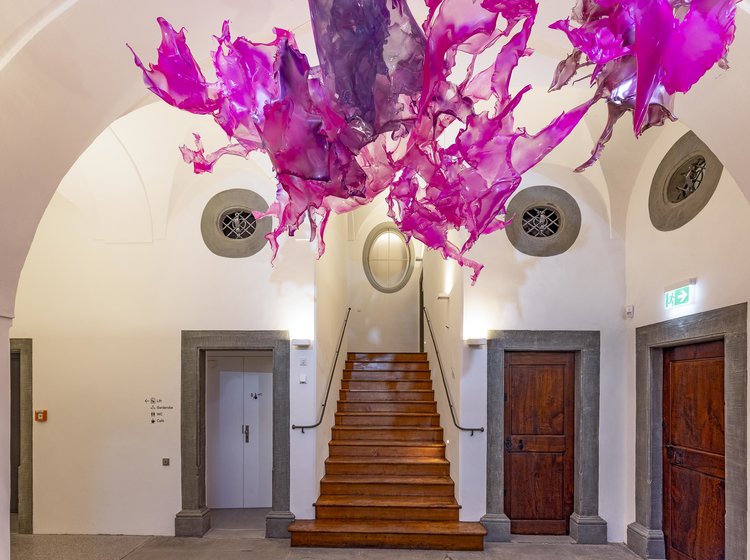 Treppenhaus mit moderner Kunstinstallation Historisches Treppenhaus im Cavazzen Lindau mit Holzstufen und moderner, pink-violetter Deckeninstallation.