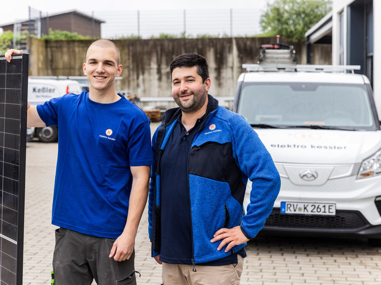 Zwei Mitarbeiter von Elektro Kessler stehen vor einem Firmenfahrzeug