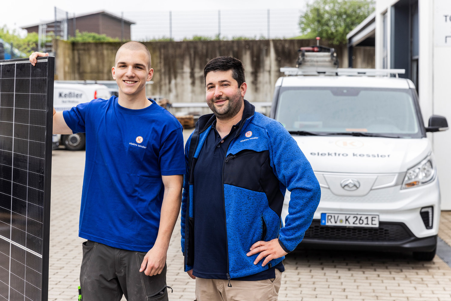 Zwei Mitarbeiter von Elektro Kessler stehen vor einem Firmenfahrzeug
