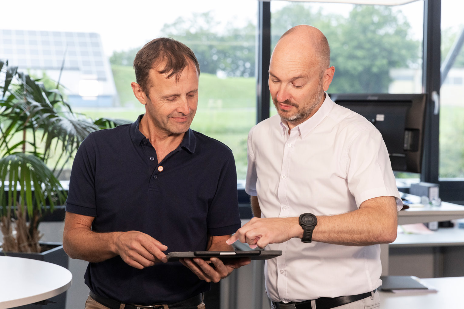 Zwei Mitarbeiter im Gespräch, einer zeigt auf ein Tablet