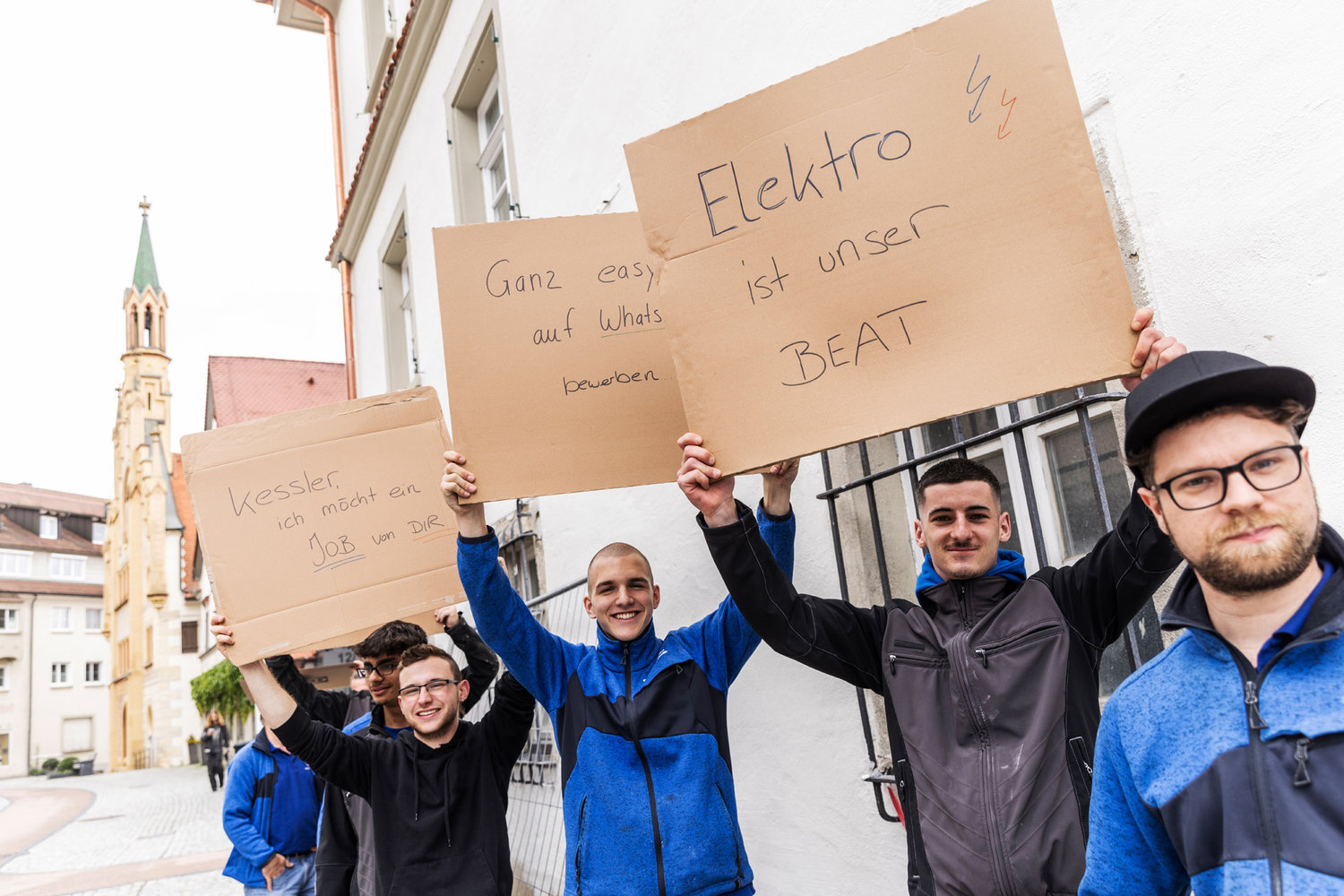 Mehrere junge Männer halten beschriebene Schilder hoch